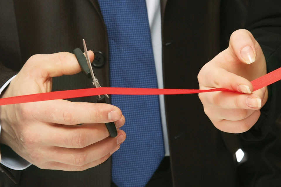 Red tape being cut with a pair of scissors